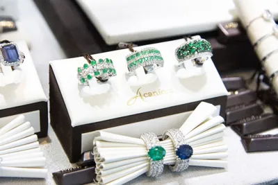 Rings with green and blue stones displayed on a white stand.
