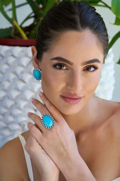 Model wearing natural turquoise earrings and ring in 18kt white gold with natural diamonds and sapphires