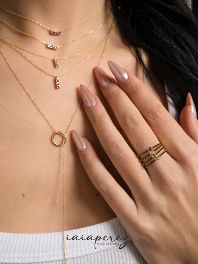 Model wearing pink sapphire and sky blue topaz necklaces and gemstone rings in 9kt gold, iaiaperez