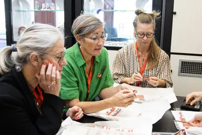 Three buyers examining coral jewellery laid out on a table.