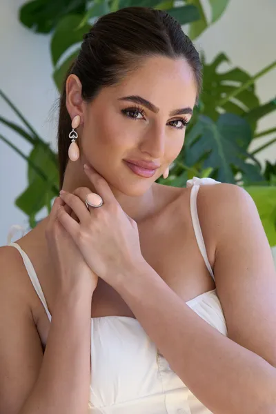 Model wearing natural pink coral earrings and ring in 18kt white gold with natural diamonds