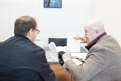 Two men in conversation at a meeting table.