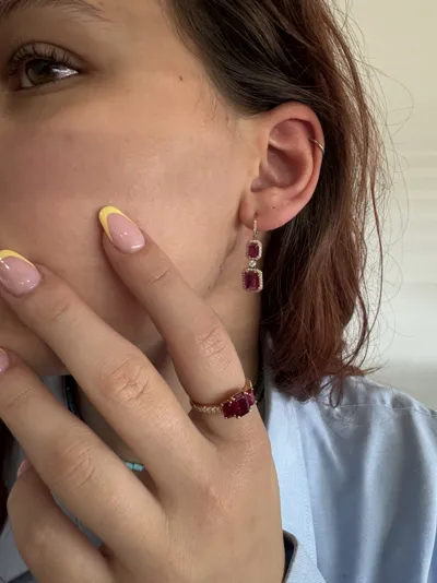 Model wearing an 18Kt yellow gold ring and earrings with emerald-cut rubies and diamonds