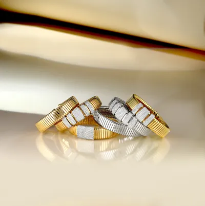 Stack of Tubogas bracelets in yellow and white gold with diamond pavé bars