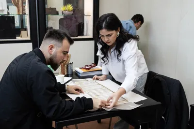 An exhibitor and a buyer looking over documents at a meeting table.
