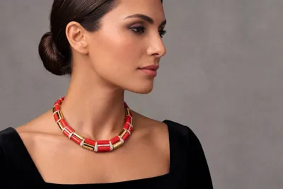 Model wearing a collar necklace in 18ct yellow gold with red coral and diamonds