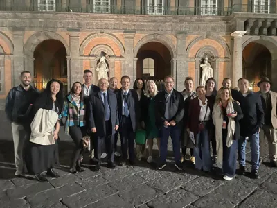 The buyers' delegation in a group photograph at night in front of a historic palace.