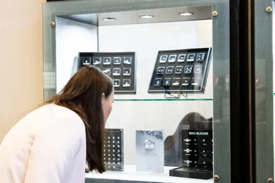 A visitor leaning in to look at jewellery in a glass showcase.