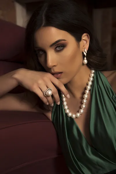 Model wearing a white pearl necklace with matching pearl drop earrings and ring