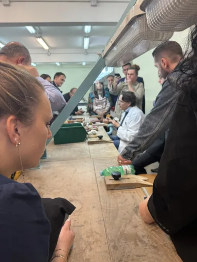 Visitors watching artisans at work along a workbench.