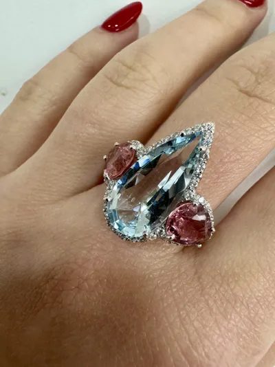 Hand wearing an 18Kt white gold ring with an aquamarine drop, two tourmaline drops and diamonds