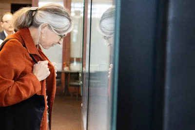 A visitor in an orange jacket looking closely at a showcase.
