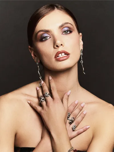 Model wearing silver snake rings and long snake earrings from the Aghatos collection