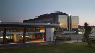Il Tarì Gold Centre in Marcianise at dusk: glass pavilions lit from inside.