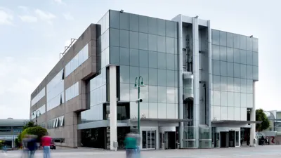 A glass and steel building of Il Tarì Gold Centre under a clear sky.