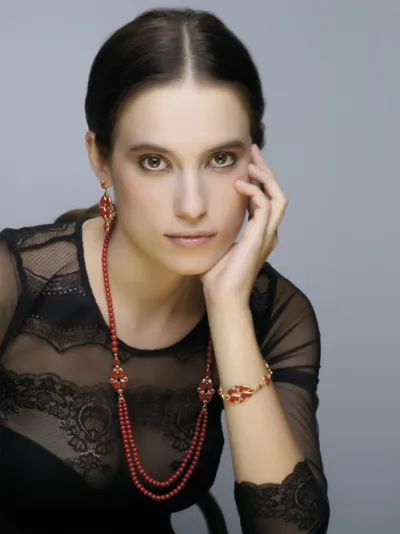 Model wearing coral and yellow gold drop earrings, necklace and bracelet, Arabesque line