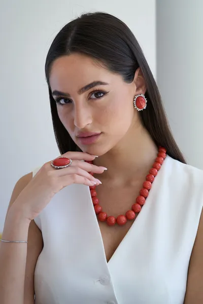 Model wearing a natural red coral necklace, earrings and ring in 18kt white gold with natural diamonds